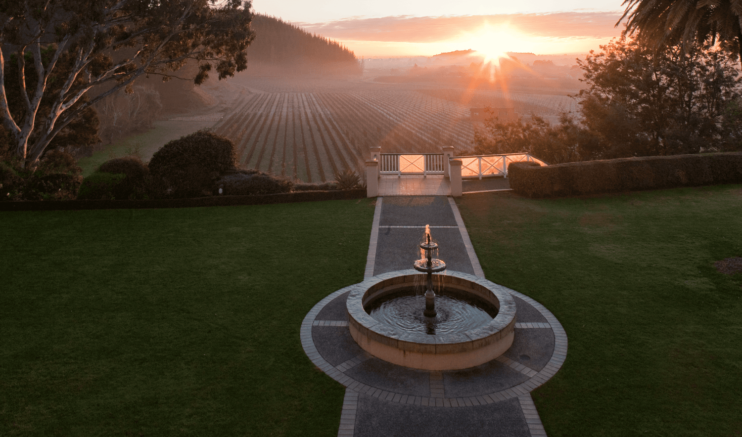 View of a fountain in the Mission Estate garden with the Mission Estate Hawke's Bay vineyard in the background